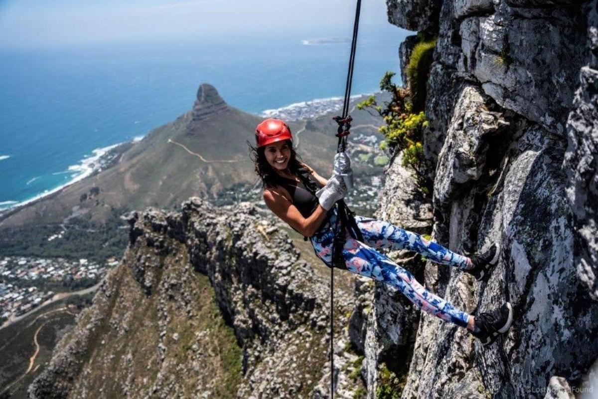una donna si sta calando in corda doppia da una montagna