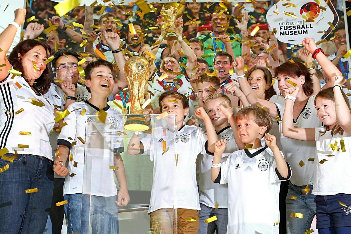 a group of children holding up the soccer league trophy