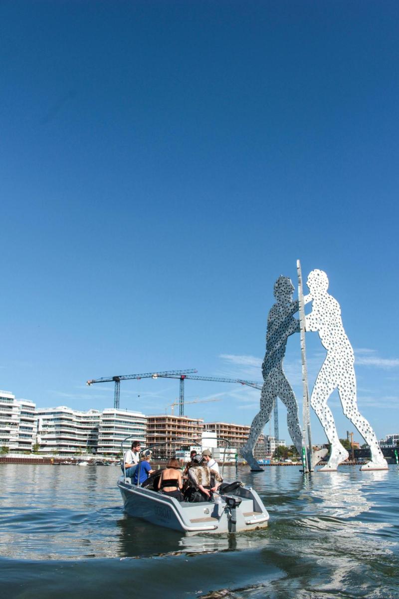un grup de oameni pe o barcă în apă cu o statuie