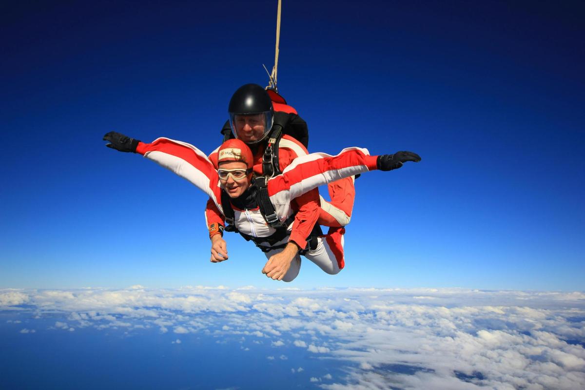 two people hanging from a rope in the sky
