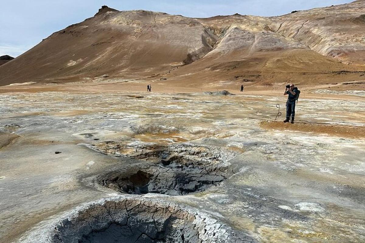 Un hombre tomando una fotografía de un desierto con montañas al fondo.