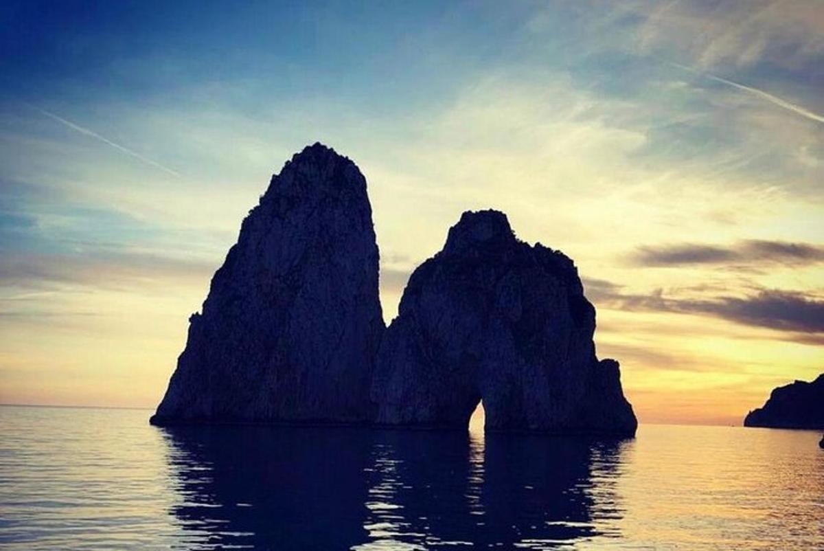 Un grupo de rocas en el agua al atardecer