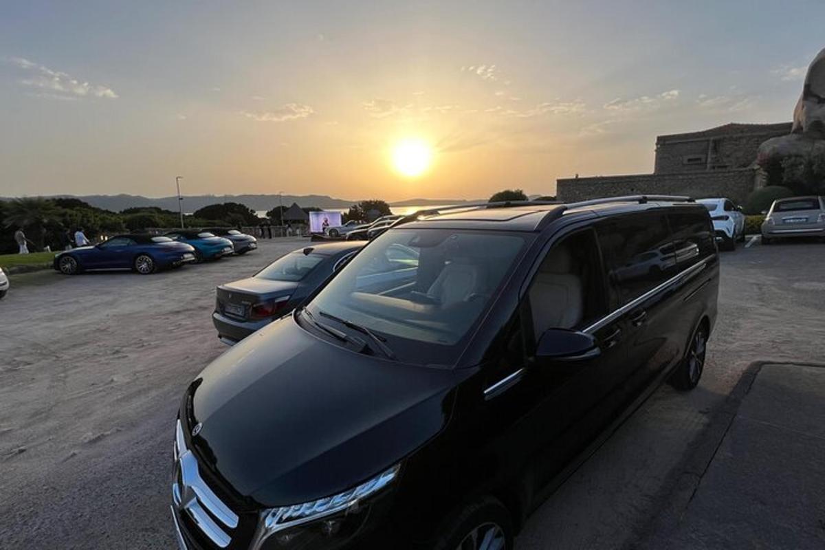 črn kombi parkiran na parkirišču s sončnim zahodom v ozadju