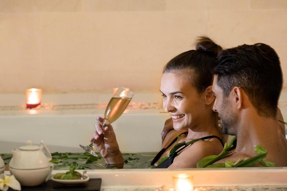 isang lalaki at babae sa isang bathtub na may isang baso ng champagne