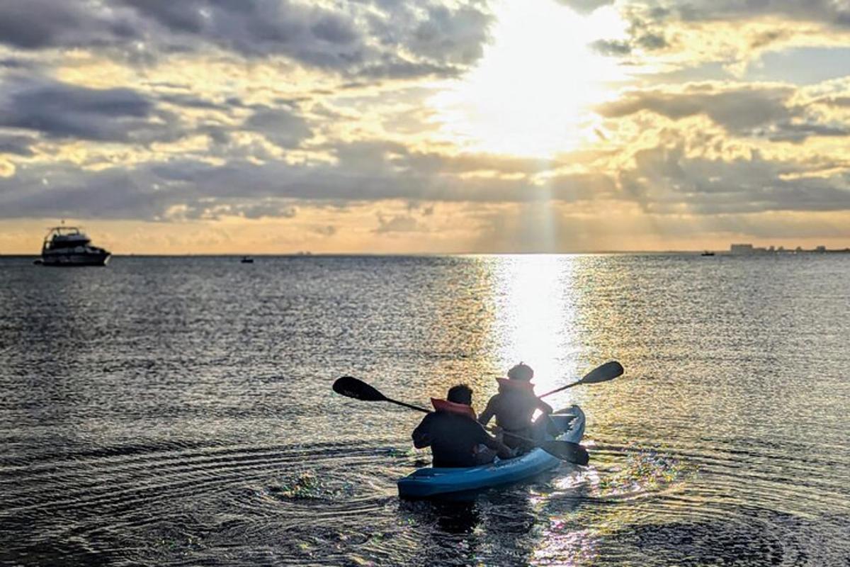 two people in a kayak on the water at sunset