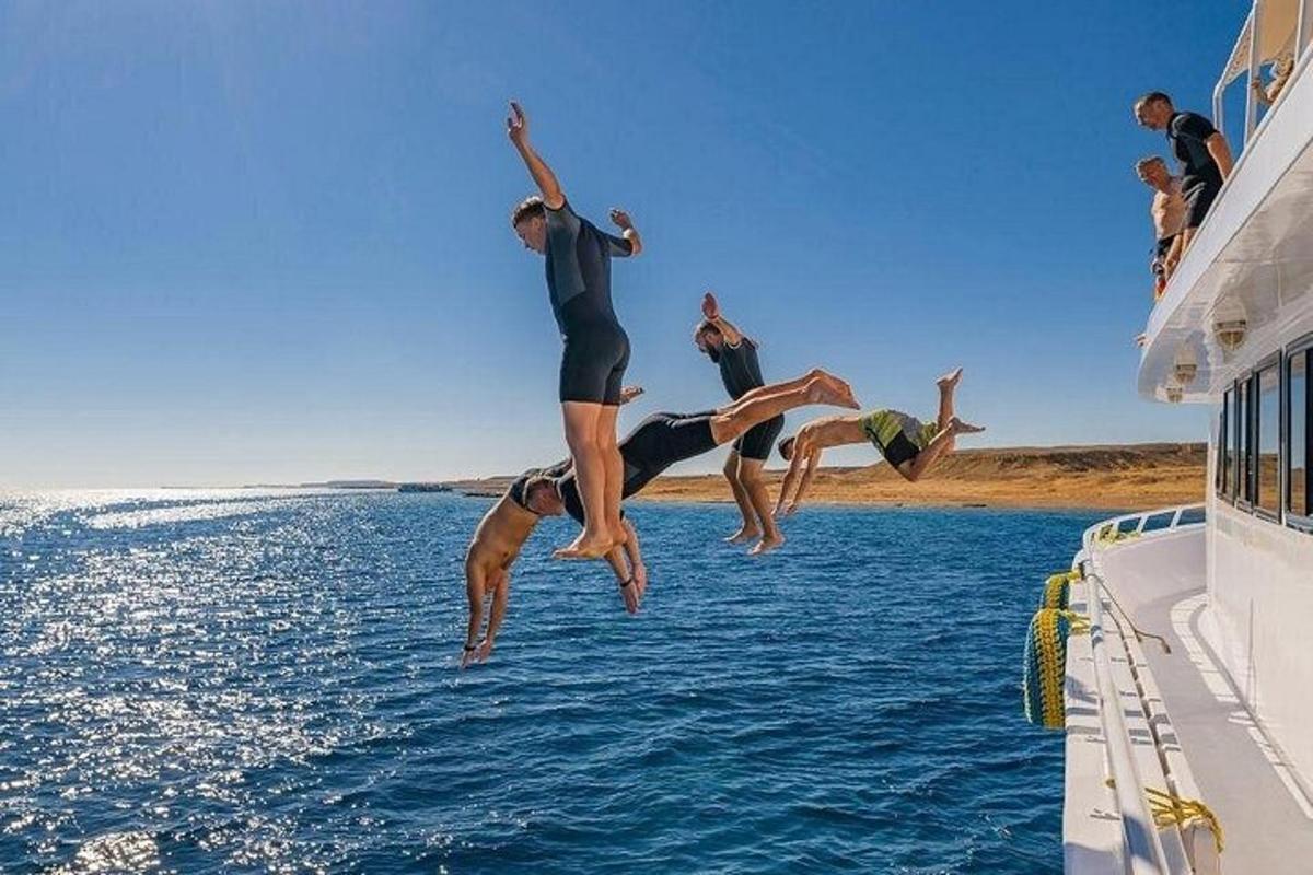 Un grupo de personas saltando al agua desde un bote.