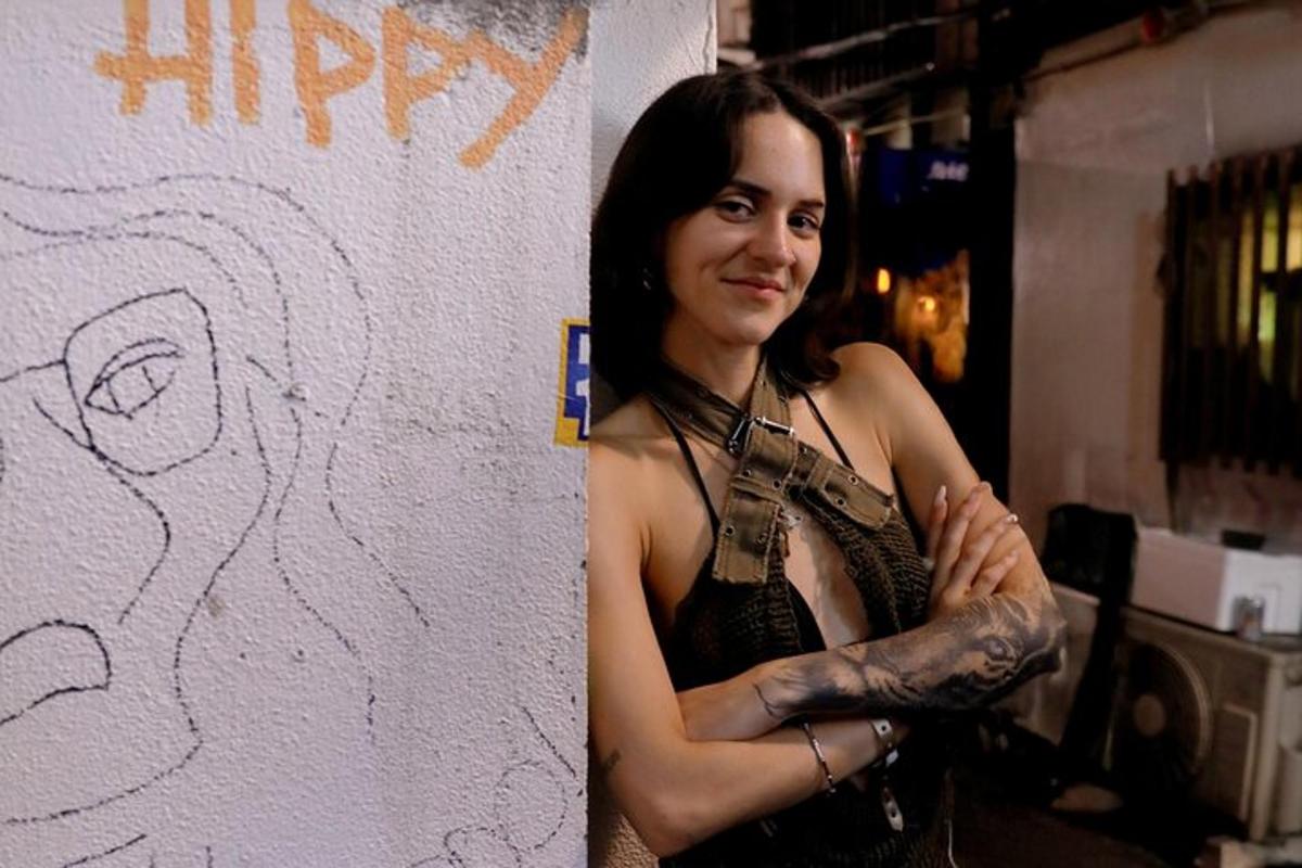 una donna con un tatuaggio sul braccio in piedi accanto a un muro