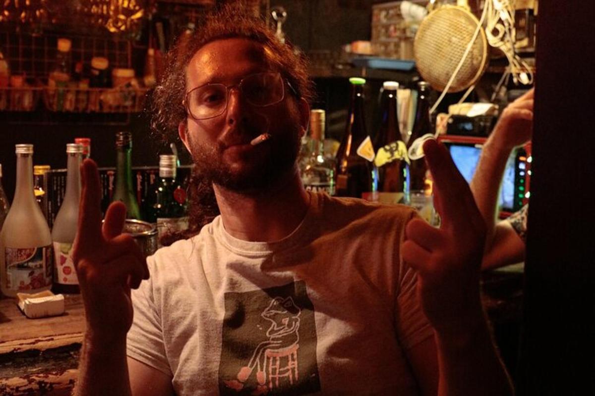 un uomo che fuma una sigaretta mentre è in piedi in un bar