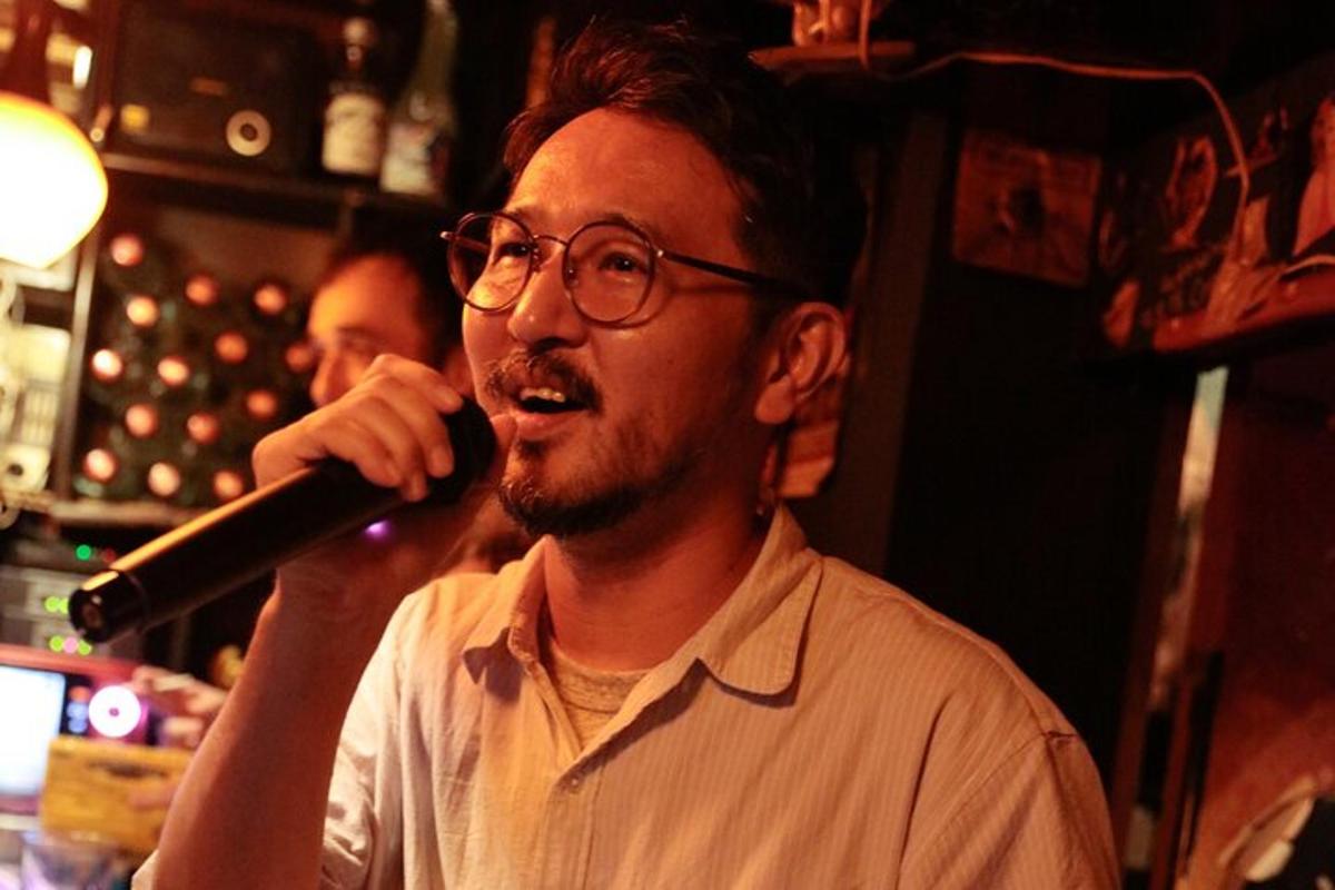 Un hombre cantando con un micrófono en un bar.