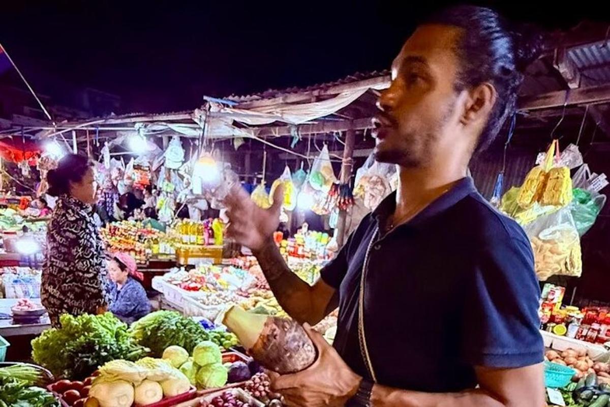 Un hombre parado en un mercado vendiendo verduras