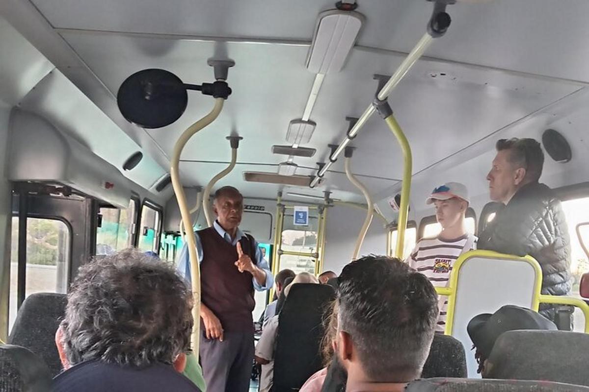 muž stojící v autobuse se skupinou lidí
