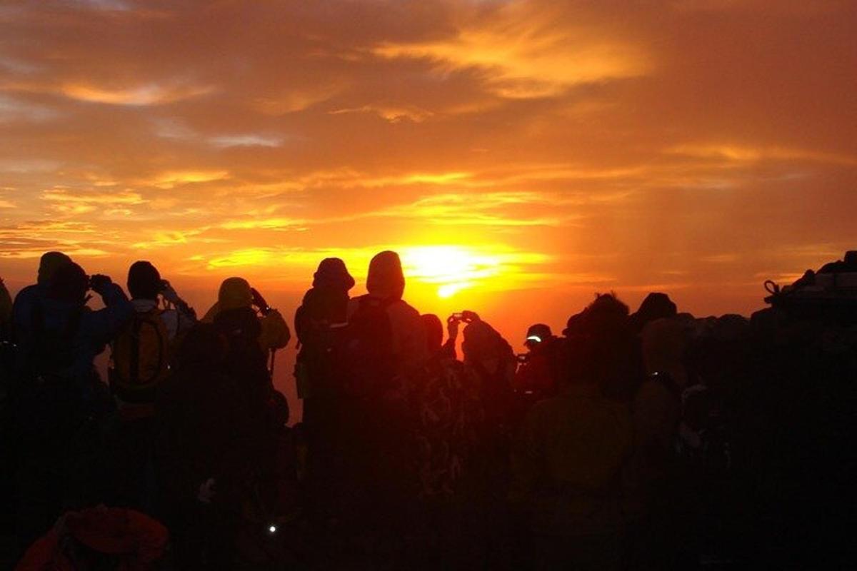 en gruppe mennesker som står foran en solnedgang