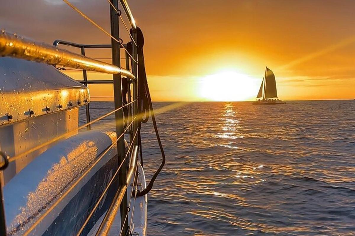 un velero en el océano al atardecer con un barco