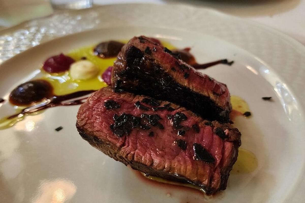 et stykke bøf på en hvid tallerken med sauce