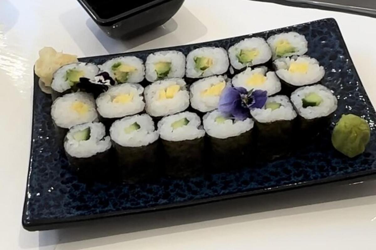 um bolo com sushi em um prato sobre uma mesa