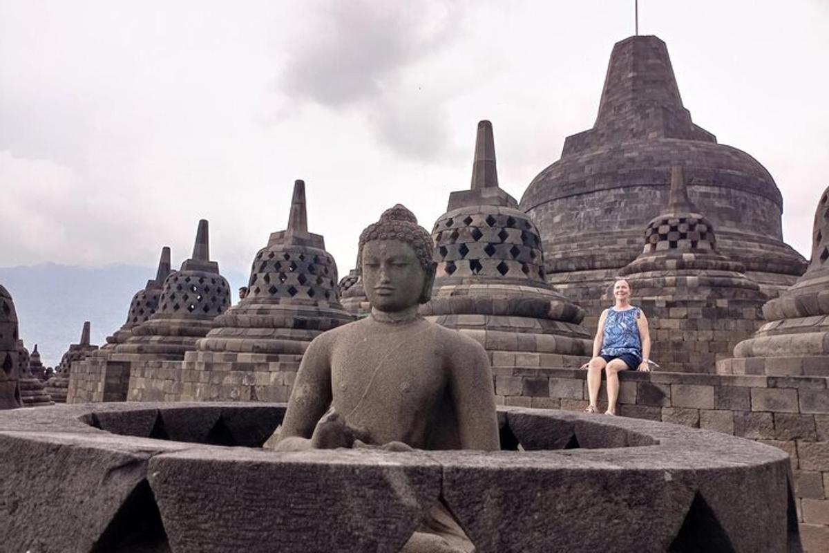 une femme assise à côté d'une statue devant un bâtiment