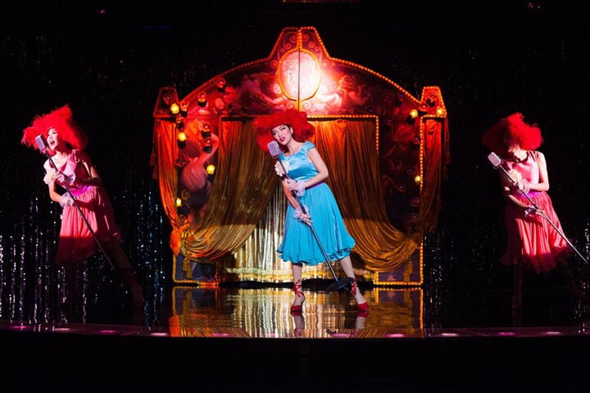 three girls are standing on a stage with a chair