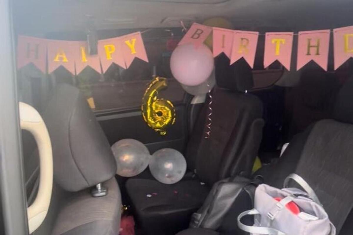 Un asiento trasero de un coche con globos y una pancarta de feliz cumpleaños.