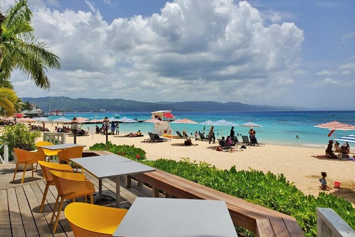 Una playa con mesas y sillas y gente en la playa.