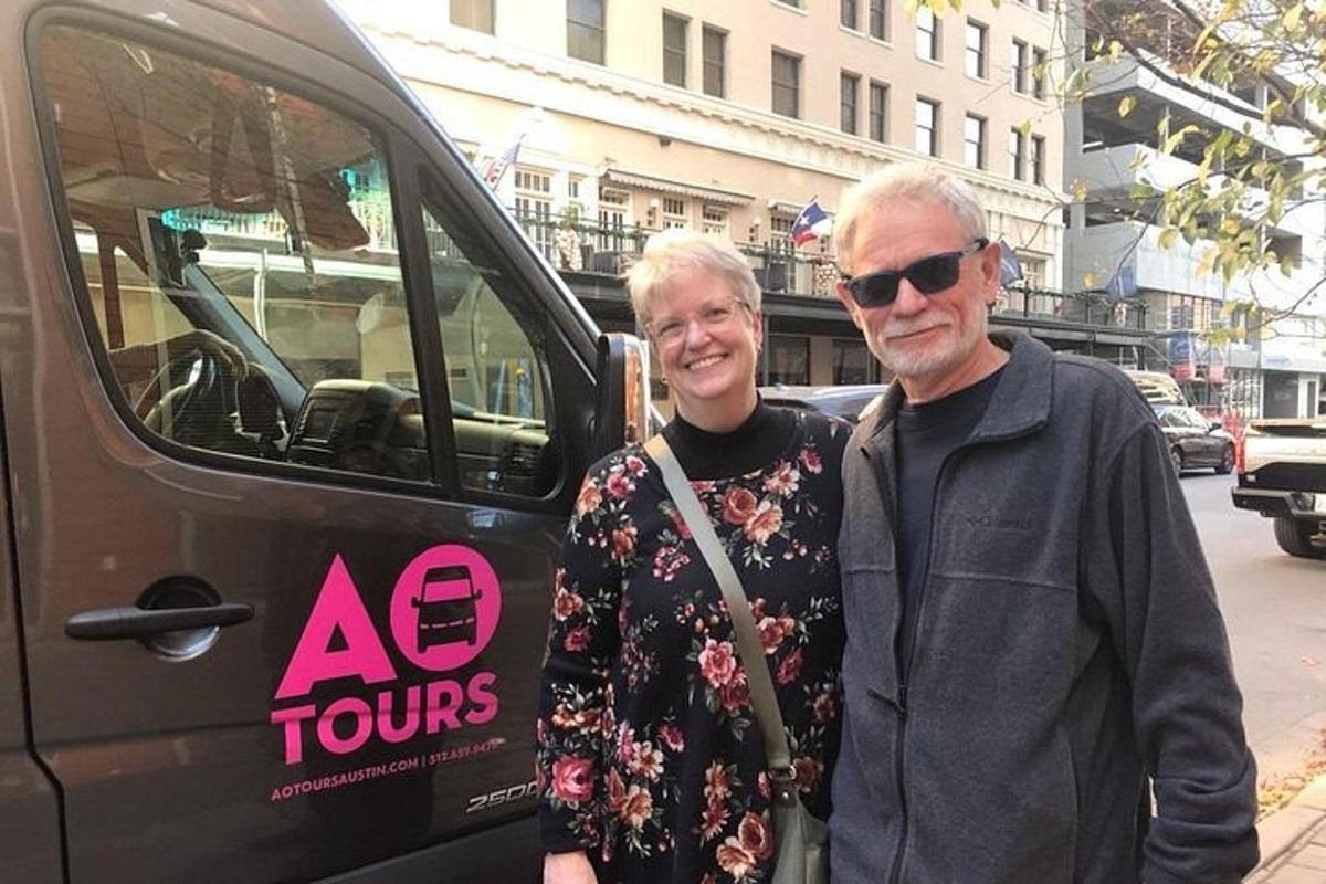 an older man and woman standing next to a bus