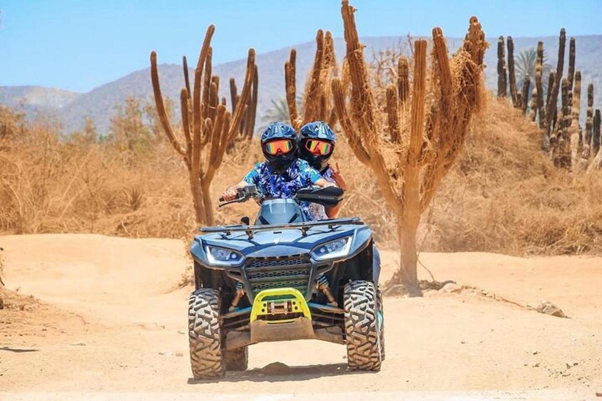 due persone a bordo di un veicolo a quattro ruote nel deserto