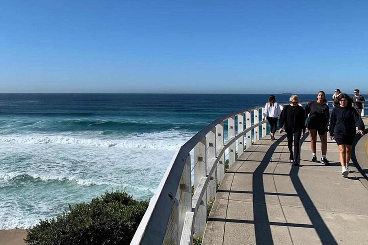 un grup de persones caminant per un passeig prop de l'oceà