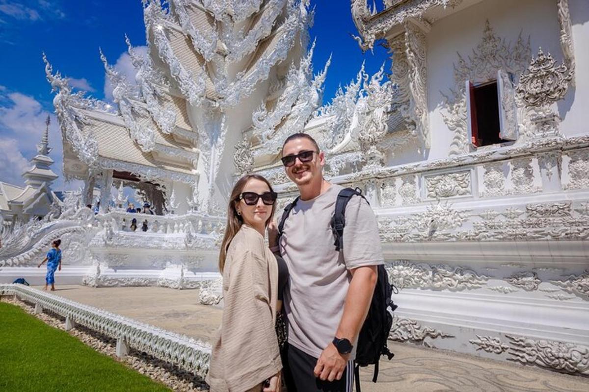 un homme et une femme debout devant un bâtiment blanc