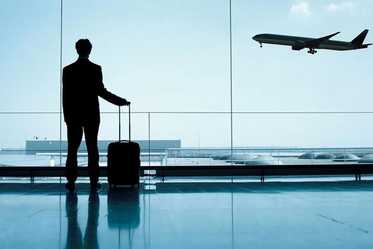 un home dret en un aeroport mirant un avió