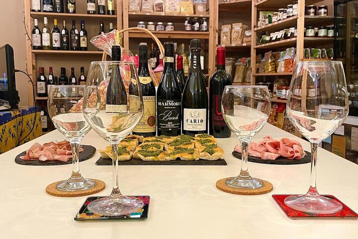patru pahare de vin așezate pe o masă cu sticle de vin