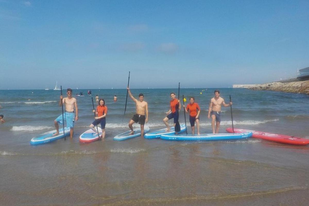 sekumpulan orang berdiri di atas papan dayung di pantai