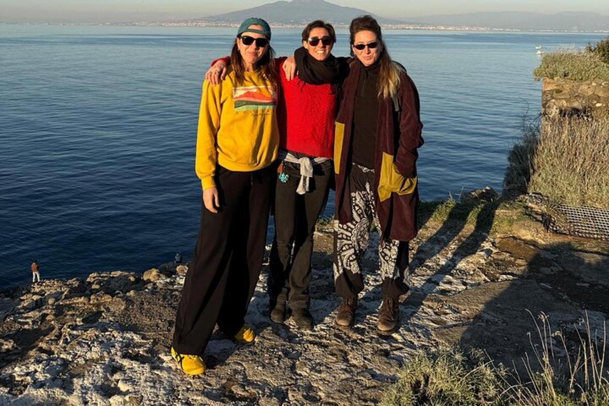 tres dones dempeus en un penya-segat a prop de l'aigua