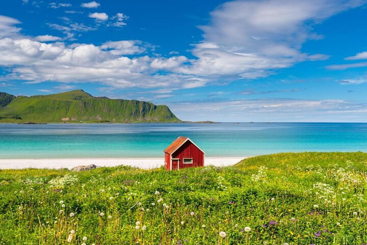 a red house sitting on a beach next to the ocean