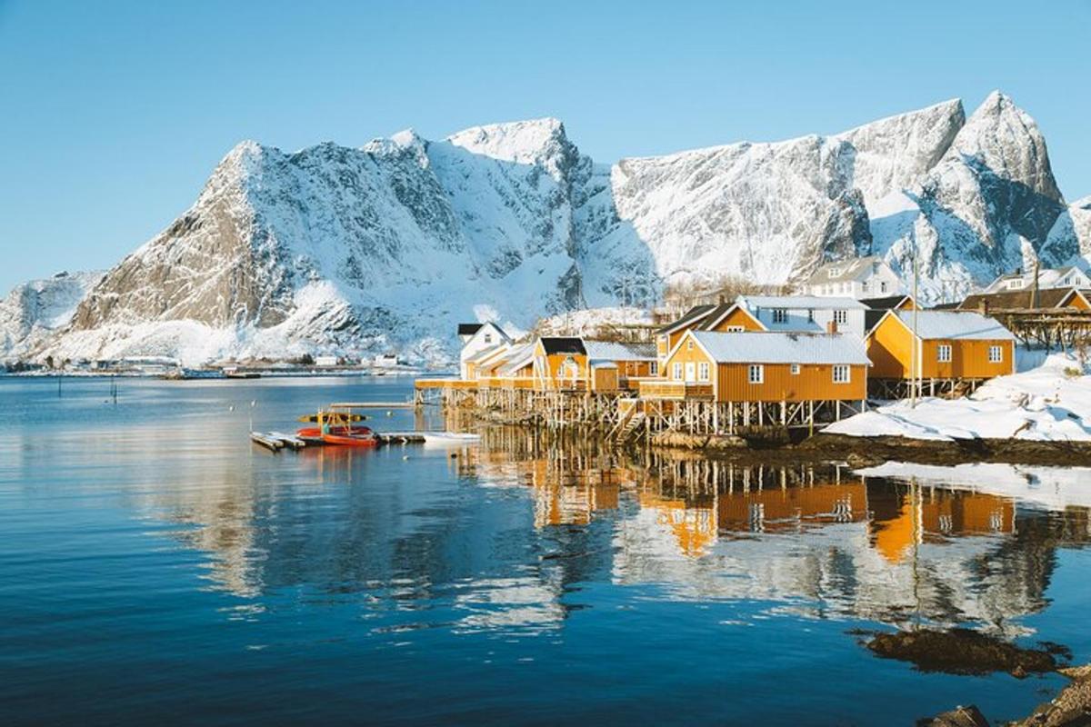 a village on a body of water with snow covered mountains
