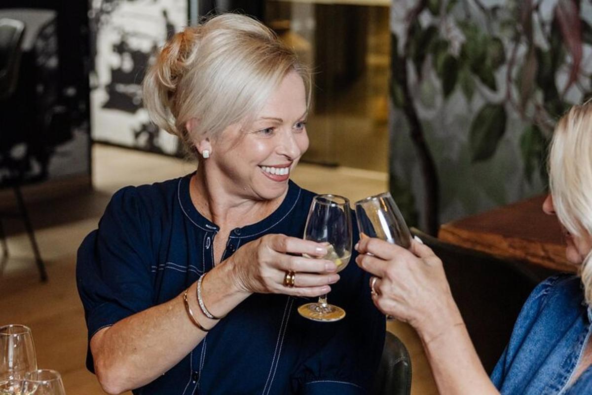 Una mujer sonriendo mientras sostiene una copa de vino