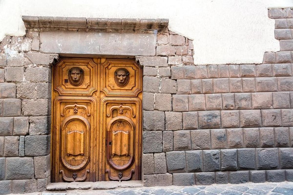 una porta di legno con dei volti sopra in un muro di mattoni