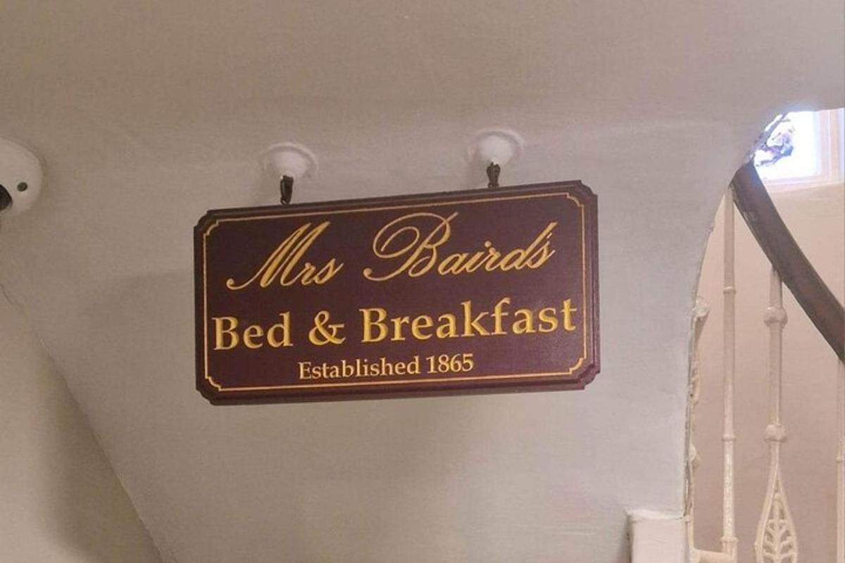 μια πινακίδα για ένα bed and breakfast κρεμασμένη σε έναν τοίχο