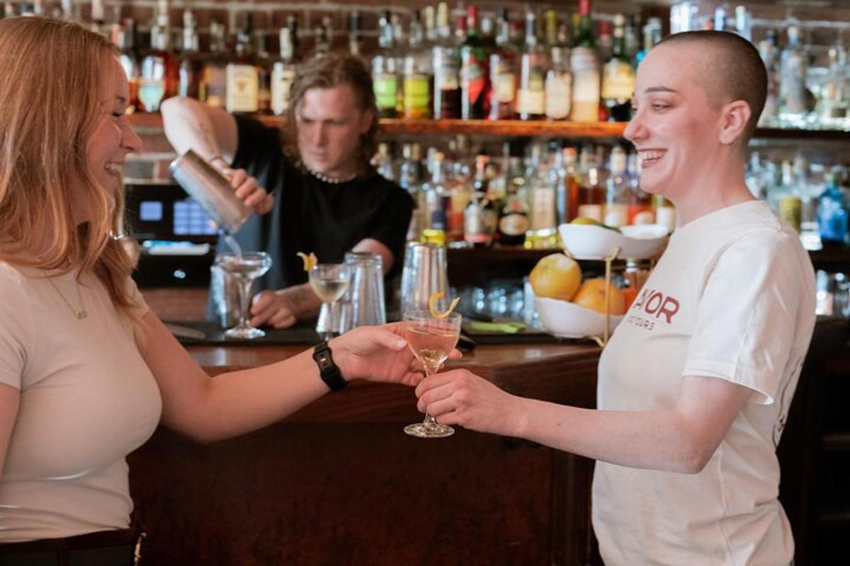 một người đàn ông và một người phụ nữ đứng ở quầy bar, tay cầm một ly rượu vang