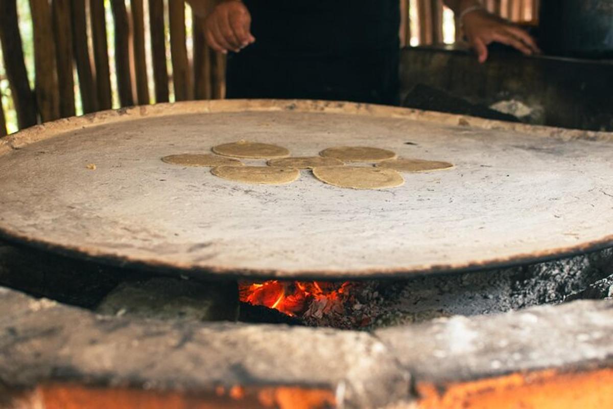 una persona que cuina menjar en una paella sobre el foc
