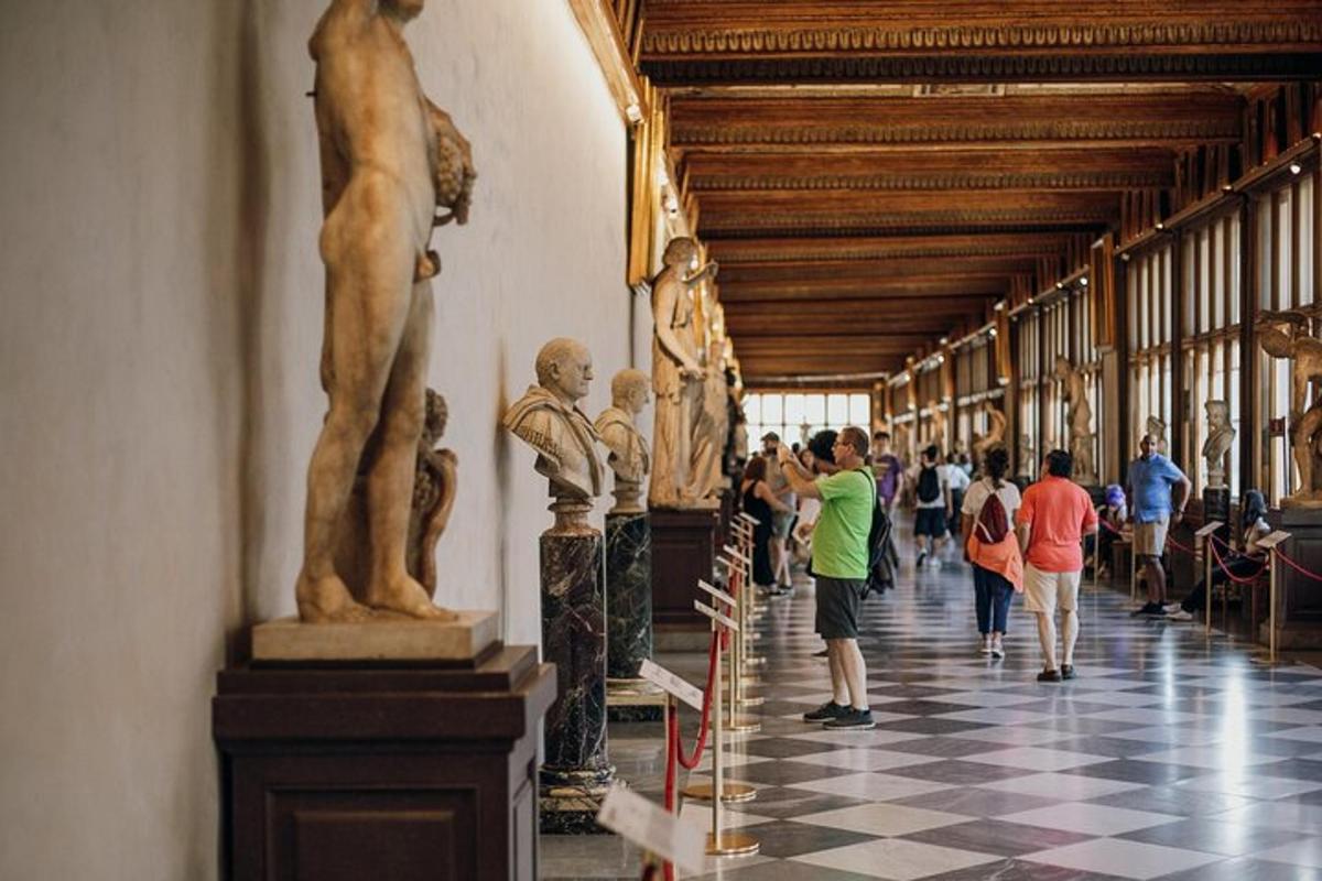 persone che camminano in un corridoio con statue in un museo