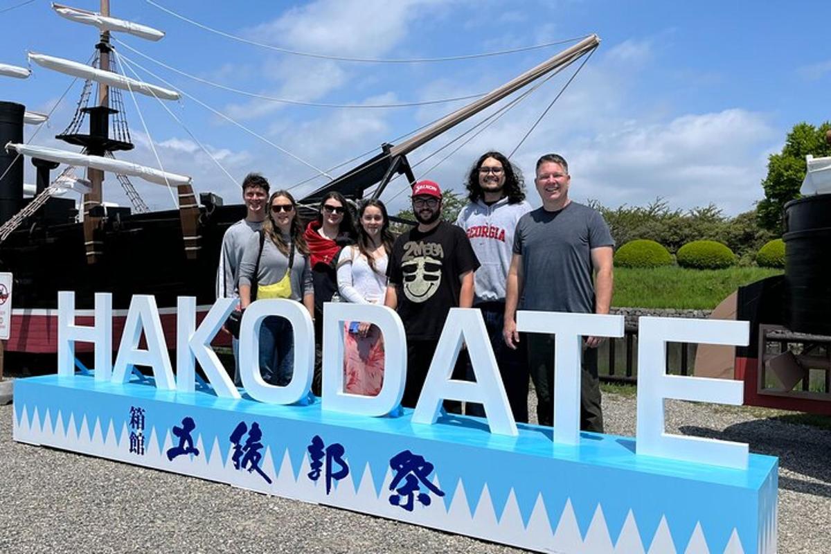 một nhóm người đứng sau một tấm biển ghi chữ shakobiarf