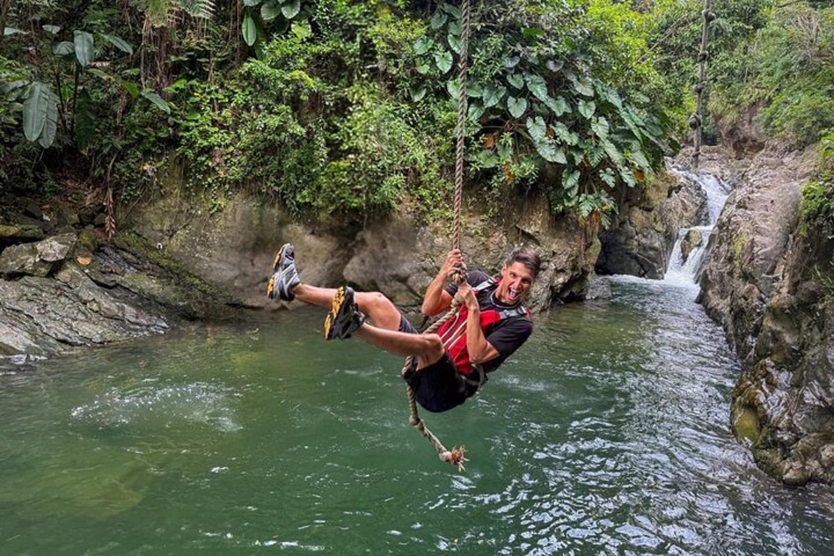 a man hanging from a rope swing over a river