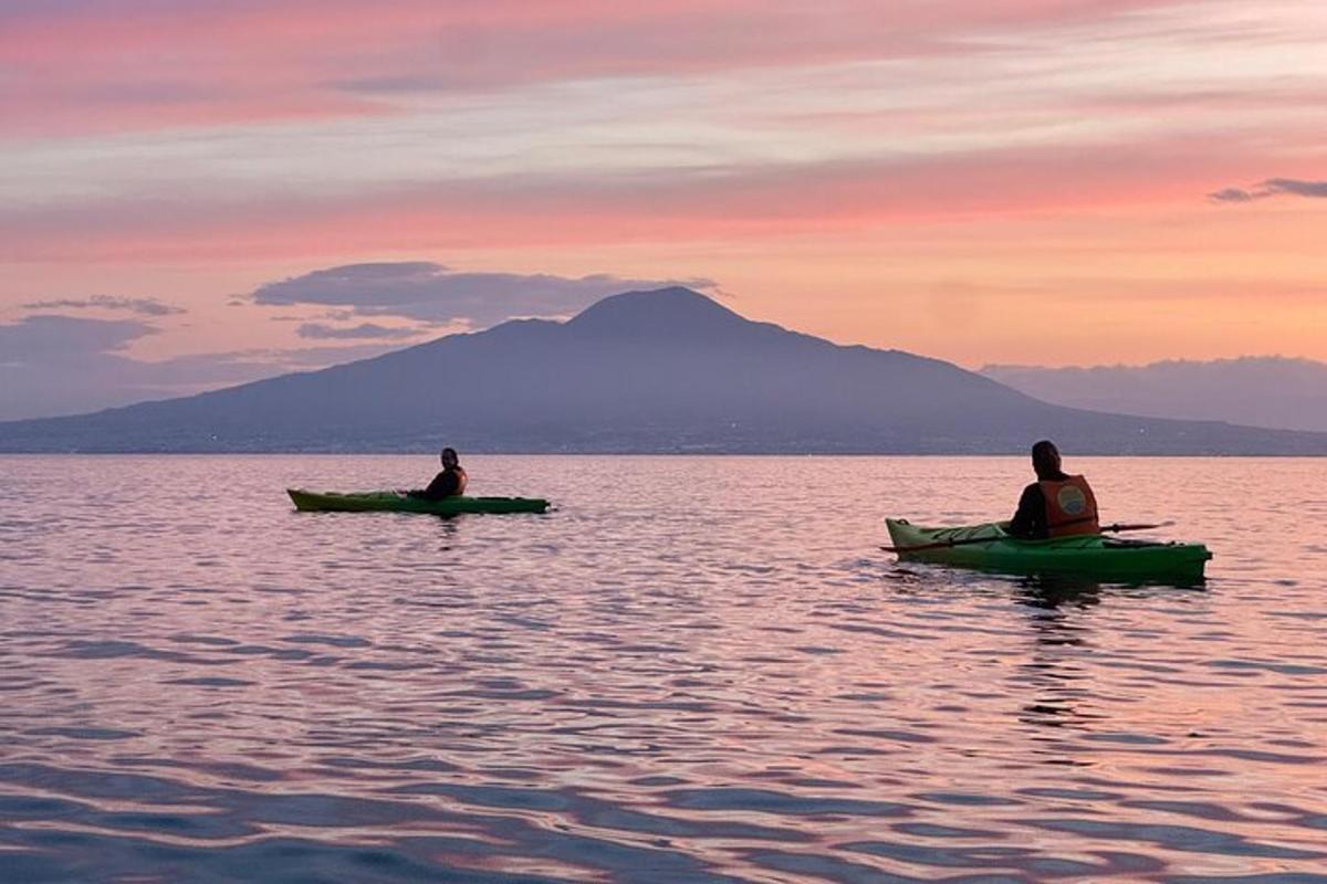 dua orang duduk di dalam kayak di dalam air pada waktu matahari terbenam