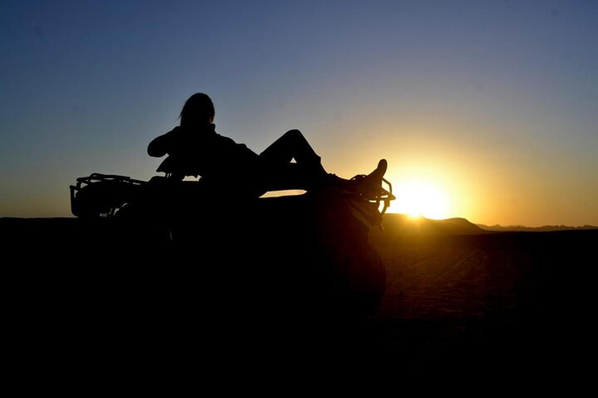 una dona asseguda a sobre d'un vehicle davant de la posta de sol