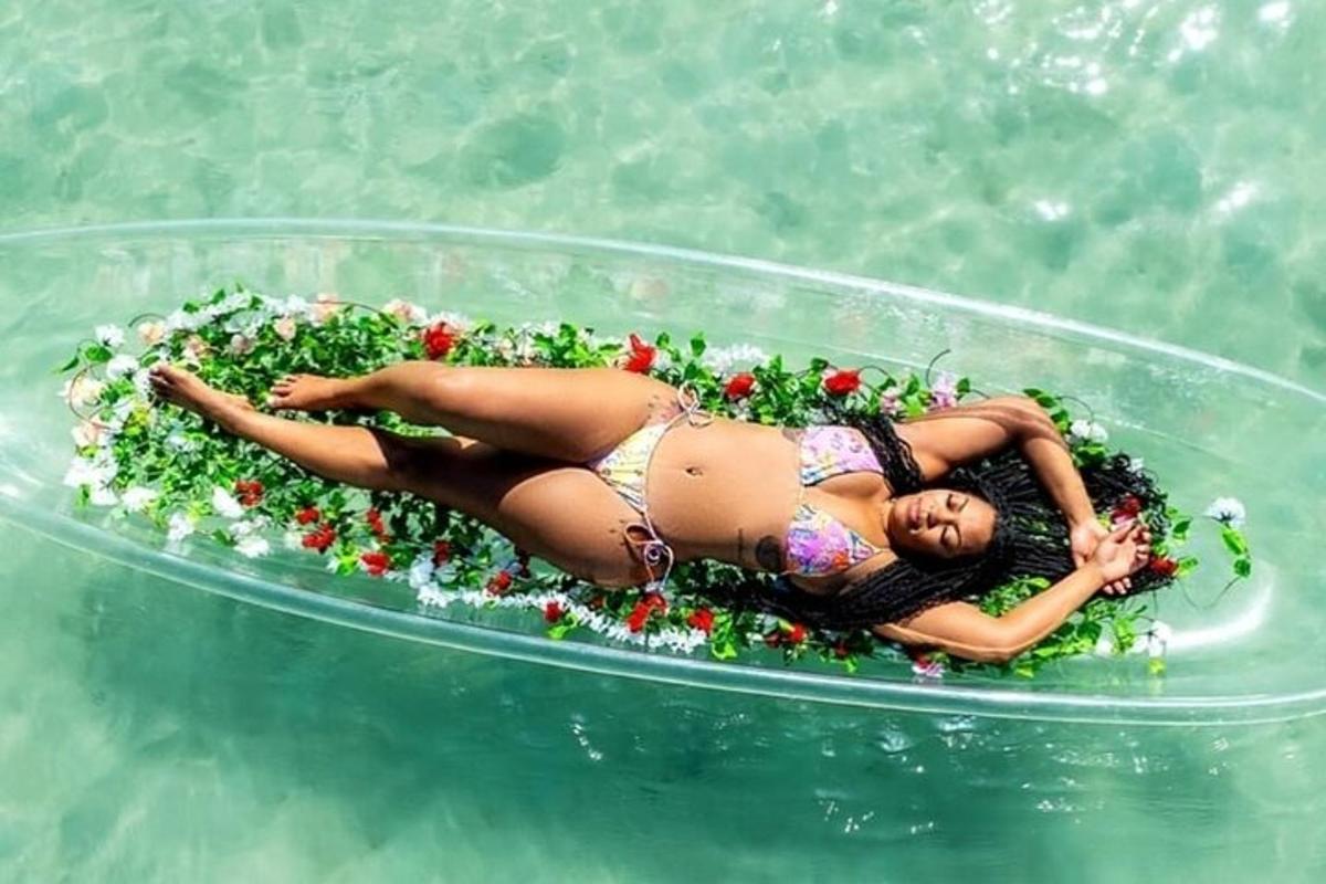 Una mujer está tumbada en una piscina inflable en el agua.