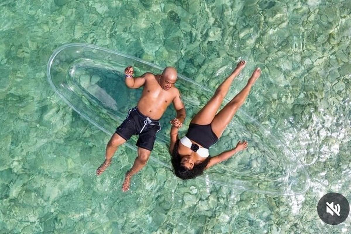 Dos personas flotando en una botella de plástico en el agua.