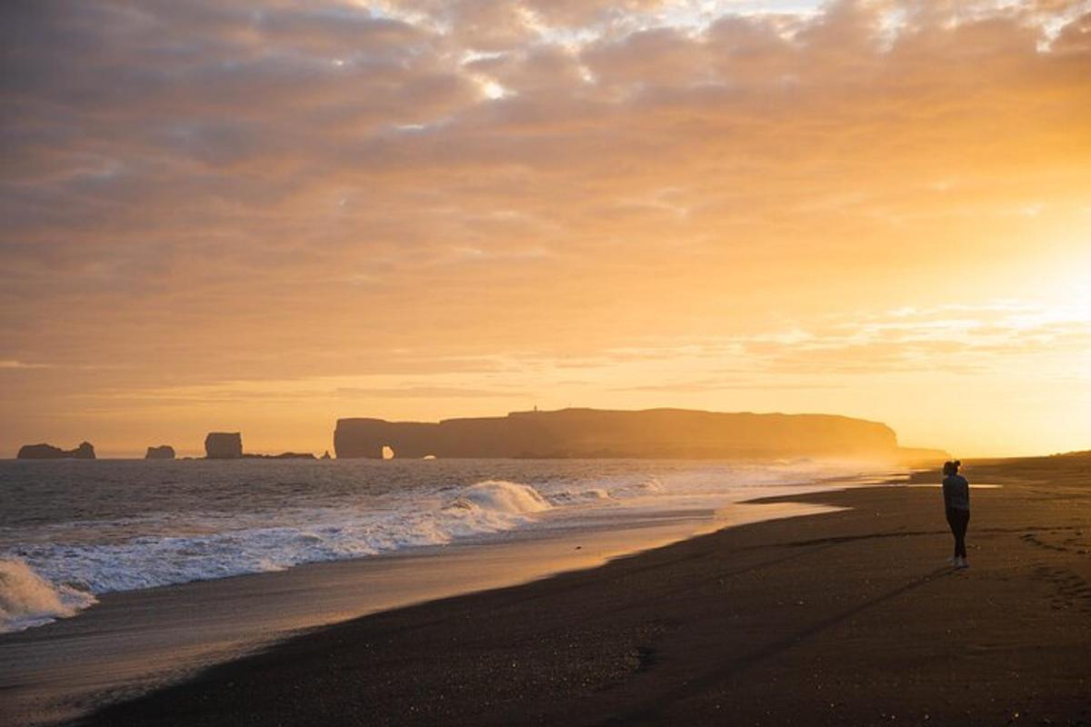 una persona caminant per la platja a la posta de sol