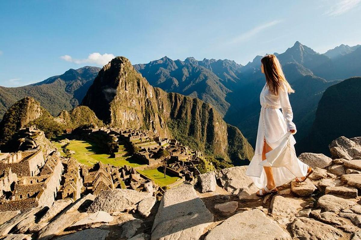 una dona amb un vestit blanc dempeus al cim d'una muntanya