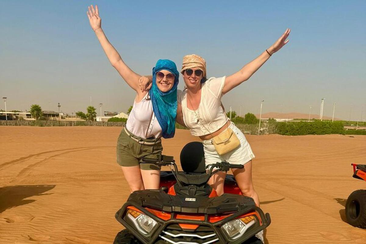 due donne in piedi accanto a una motocicletta nel deserto