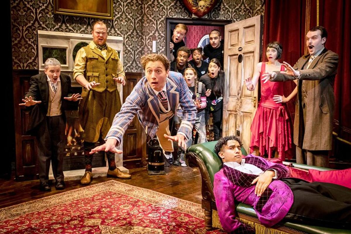 un grup de persones en un teatre amb un home estirat en un sofà