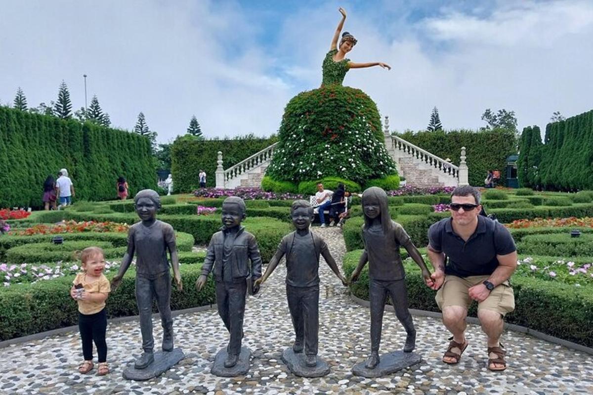 vyras klūpo šalia vaikų grupės statulos